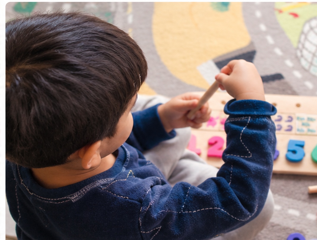 A toddler playing with a colourful number puzzle